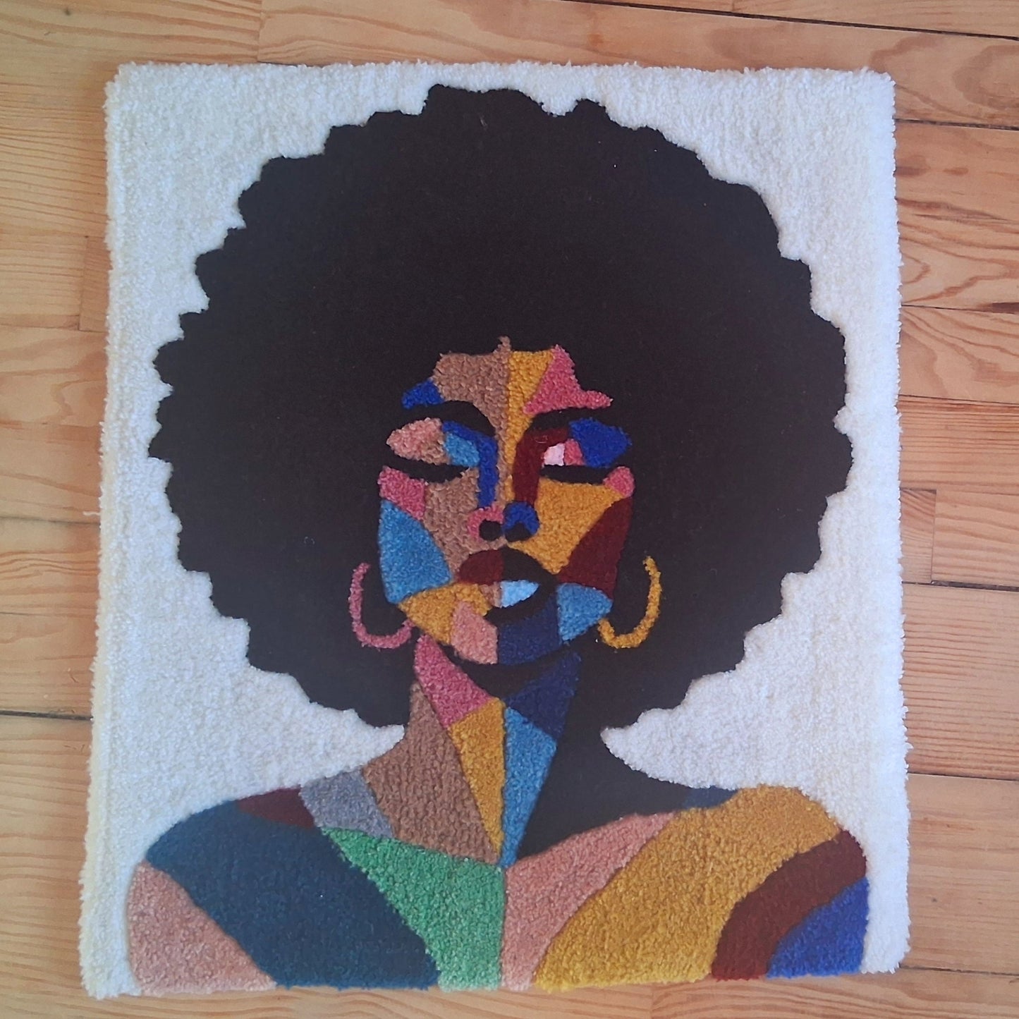 Décoration murale représentant un portrait d'une femme noire, créée par La Balmo Tufitng. Laine acrylique multicolore