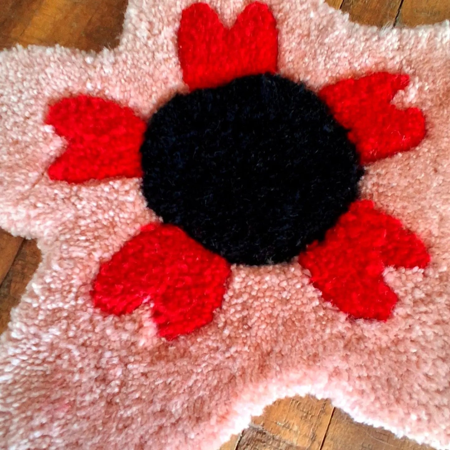 Décoration murale représentant une fleur rose, créée par La Balmo Tufting. Laine acrylique rose noire et rouge