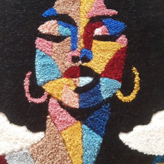 Zoom sur une décoration murale représentant un portrait d'une femme noire, créée par La Balmo Tufitng. Laine acrylique multicolore