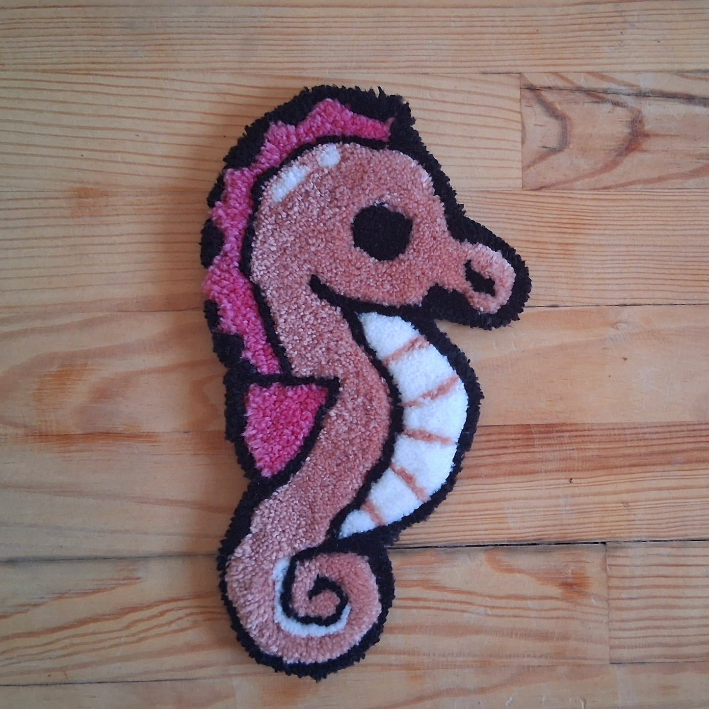 Décoration murale représentant un hippocampe rose créée par La Balmo Tufting. Laine acrylique blanche, rose et noire