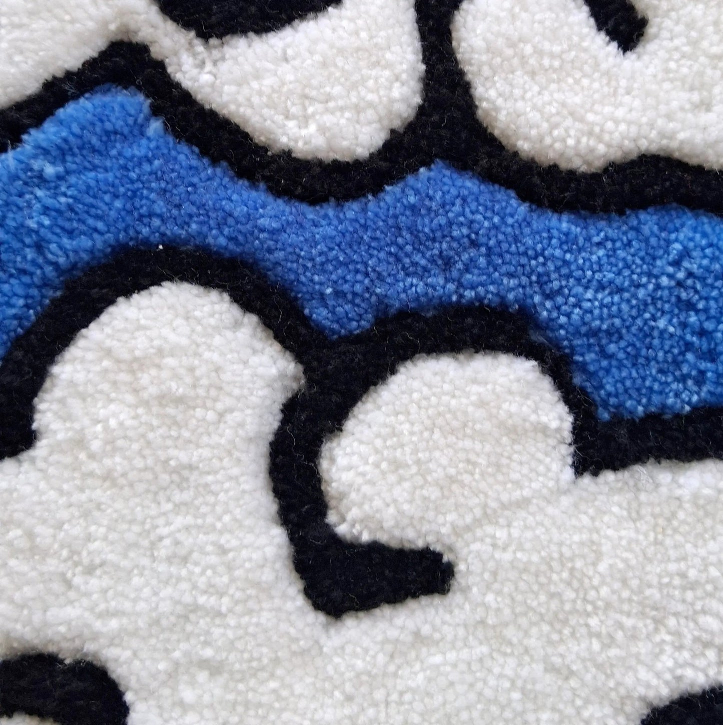 Zoom sur une décoration murale représentant des nuages dans le style japonais, créée par La Balmo Tufting. Laine acrylique bleue, blanche, noire