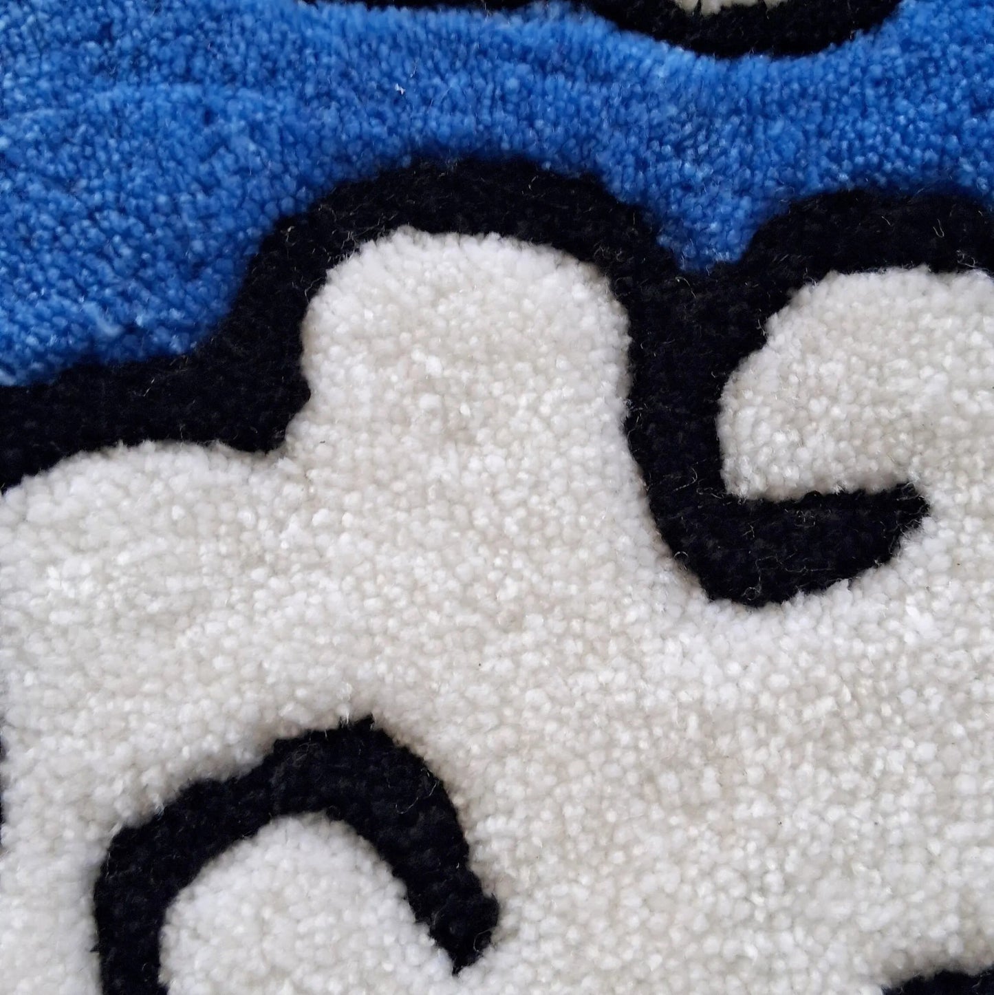 Zoom sur une décoration murale représentant des nuages dans le style japonais, créée par La Balmo Tufting. Laine acrylique bleue, blanche, noire