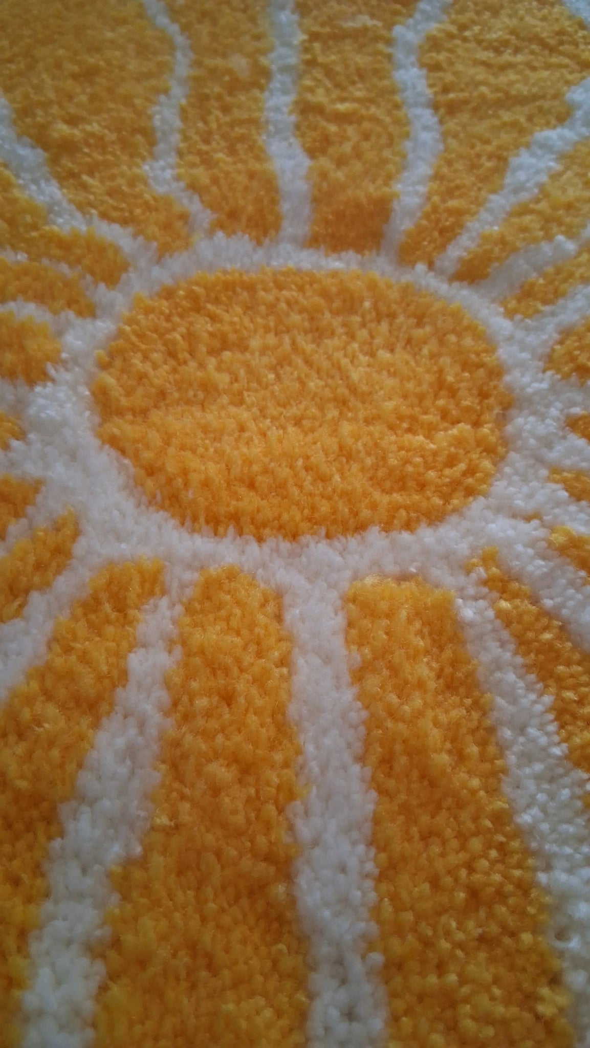 Zoom sur une décoration murale représentant un soleil dans le style japonais, créée par La Balmo Tufting. Laine acrylique jaune, blanche