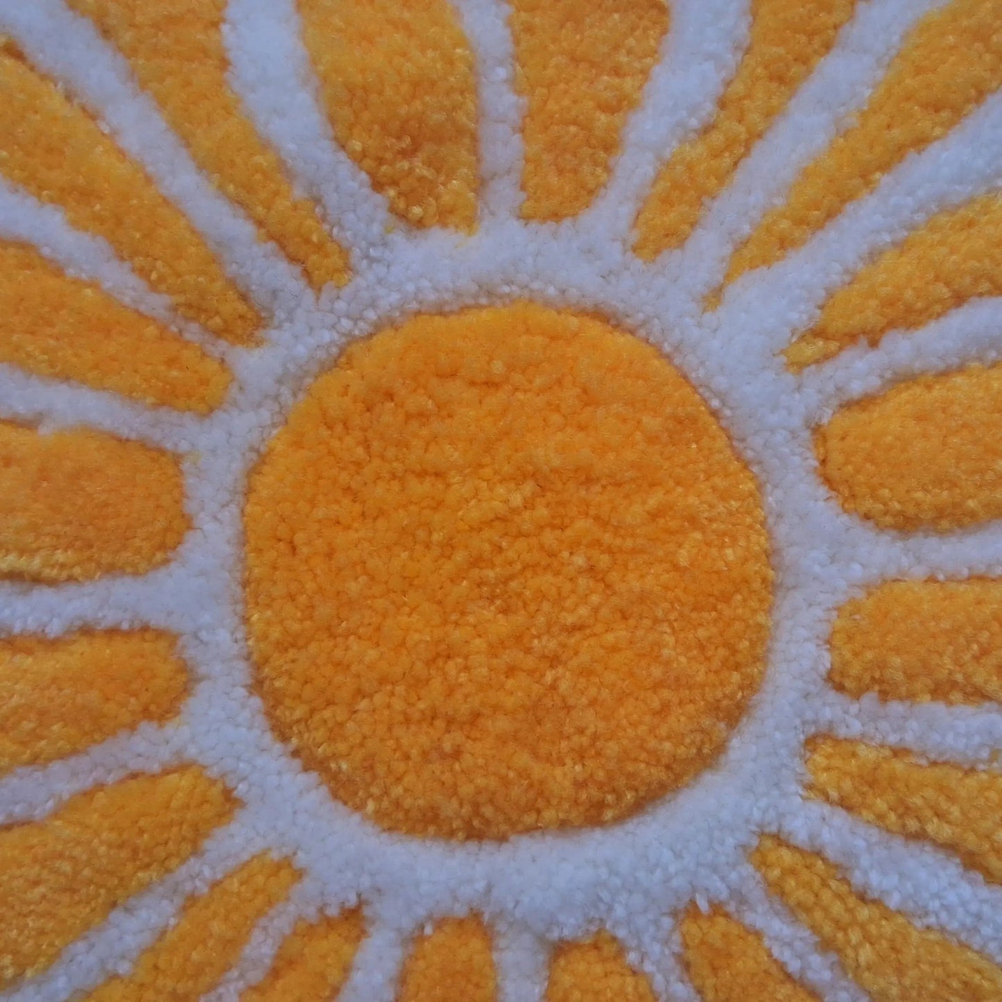 Zoom sur une décoration murale représentant un soleil dans le style japonais, créée par La Balmo Tufting. Laine acrylique jaune et blanche