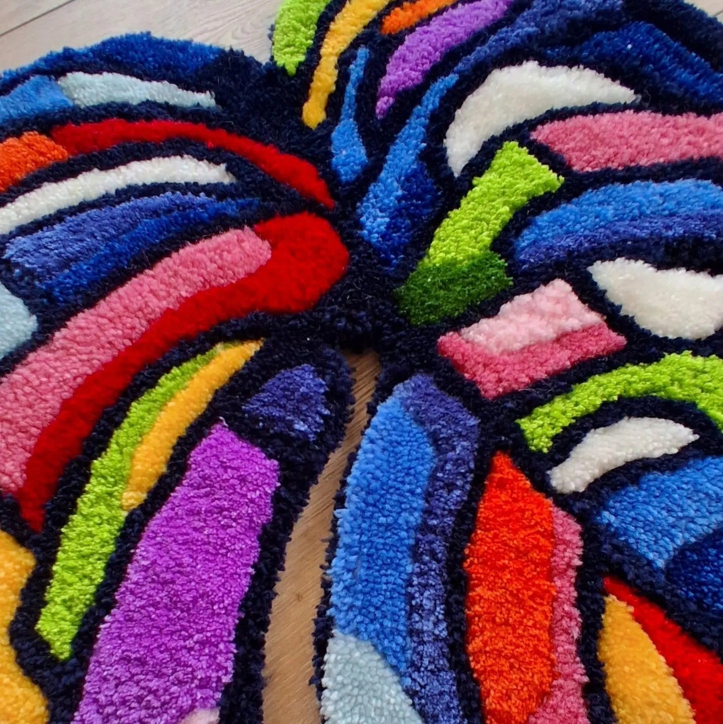 Zoom sur une décoration murale représentant une feuille de monstera multicolore, créée par La Balmo Tufting. Laine acrylique multicolore