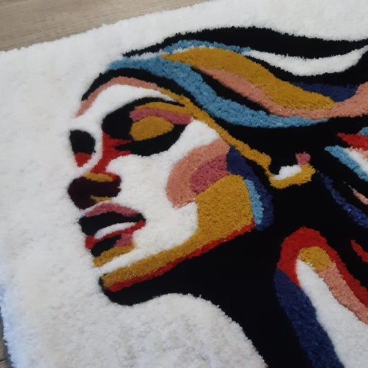 Zoom sur une décoration murale représentant un portrait d'une femme, créée par La Balmo Tufitng. Laine acrylique multicolore