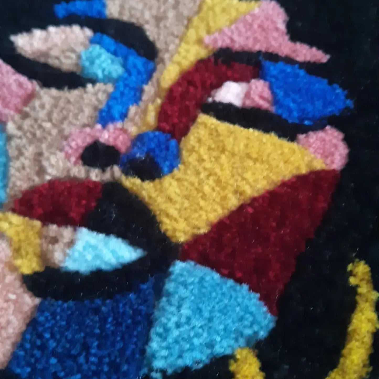 Zoom sur une décoration murale représentant un portrait d'une femme noire, créée par La Balmo Tufitng. Laine acrylique multicolore