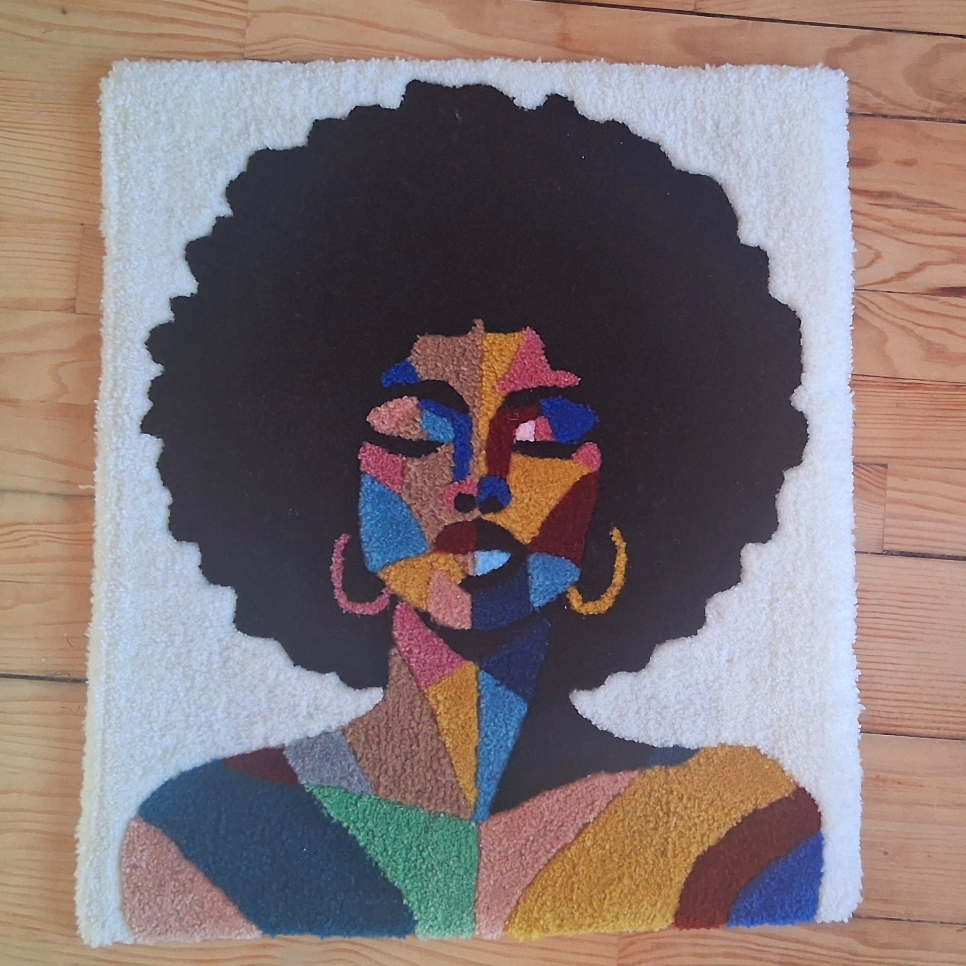 Décoration murale représentant un portrait d'une femme noire, créée par La Balmo Tufitng. Laine acrylique multicolore