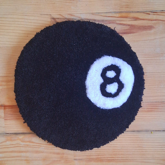 Décoration murale représentant une boule de billard numéro 8, la boule noire, créée par La Balmo Tufting. Laine acrylique noire et blanche.