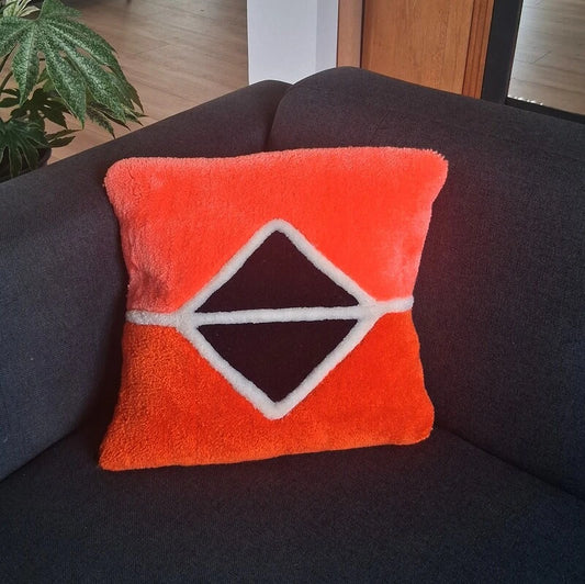 Coussin tufté mêlant les tons d'orange et de bleu foncé