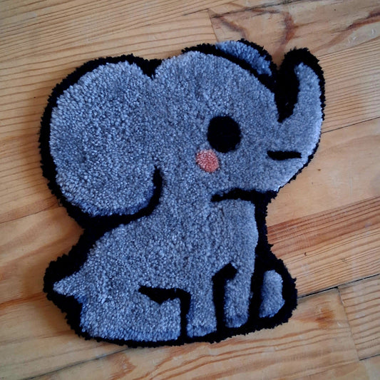 Décoration murale représentant un éléphant assis, crééé La Balmo Tufting. Laine acrylique grise, rose et noire