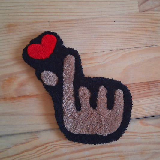 Mini décoration murale représentant un emoji coeur avec les doigts - finger heart -créée par La Balmo Tufting. Laine acrylique noire, rouge et blanche