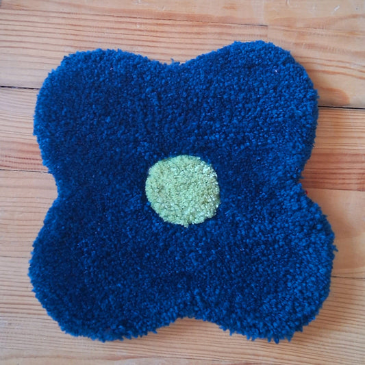 Décoration murale représentant une fleur bleue, créée par La Balmo Tufting. Laine acrylique bleue et verte