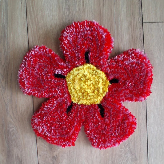 Décoration murale représentant une fleur rouge et jaune, créée par La Balmo Tufting. Laine acrylique rouge et jaune.