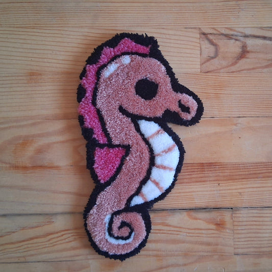 Décoration murale représentant un hippocampe rose créée par La Balmo Tufting. Laine acrylique blanche, rose et noire