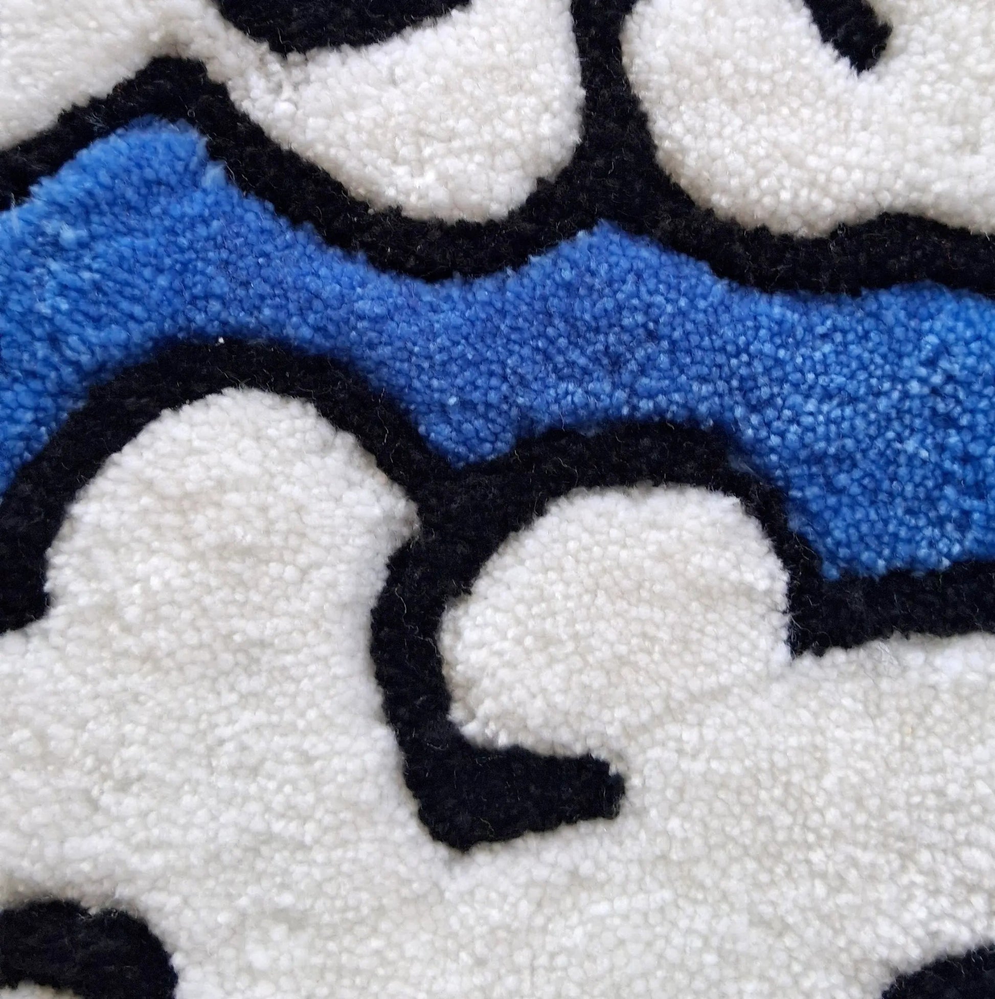 Zoom sur une décoration murale représentant des nuages dans le style japonais, créée par La Balmo Tufting. Laine acrylique bleue, blanche, noire