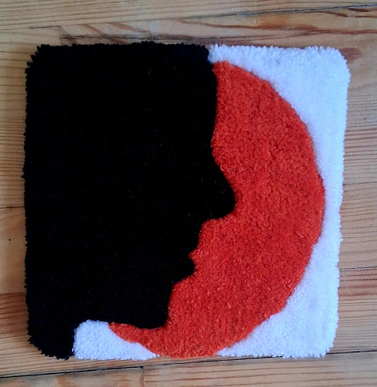 Décoration murale représentant une ombre de visage avec un soleil orange. Créée par La Balmo Tufting - Laine acrylique blanche, noire et orange