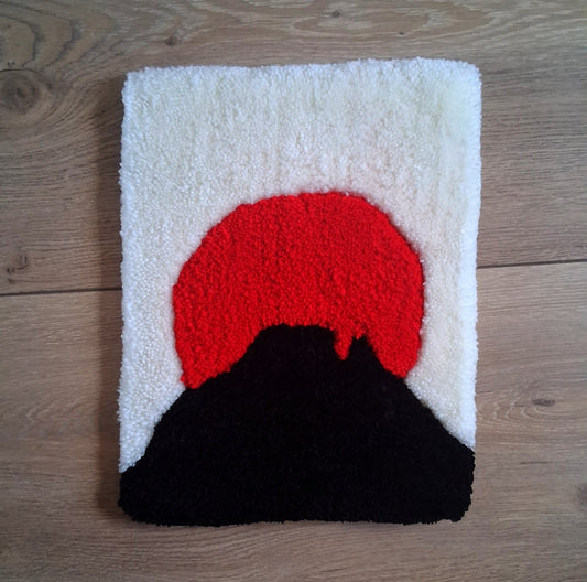 Décoration murale représentant le Pic du Midi d'Ossau dans le style japonais, avec un soleil rouge. Créée par La Balmo Tufting- Laine Acrylique rouge, noire et blanche